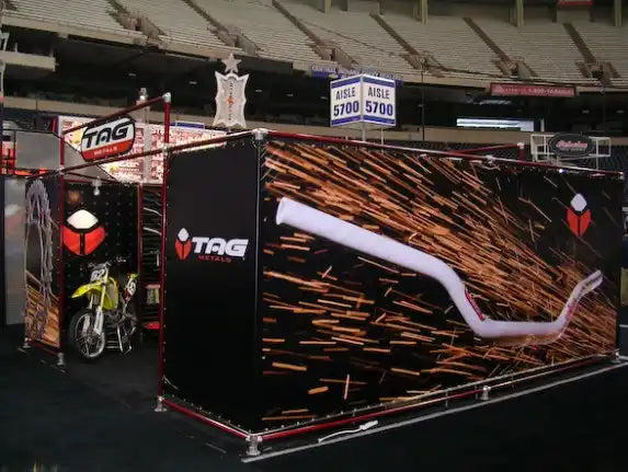 Trade show display booth with sparks/metal shavings graphics and motorcycle imagery.