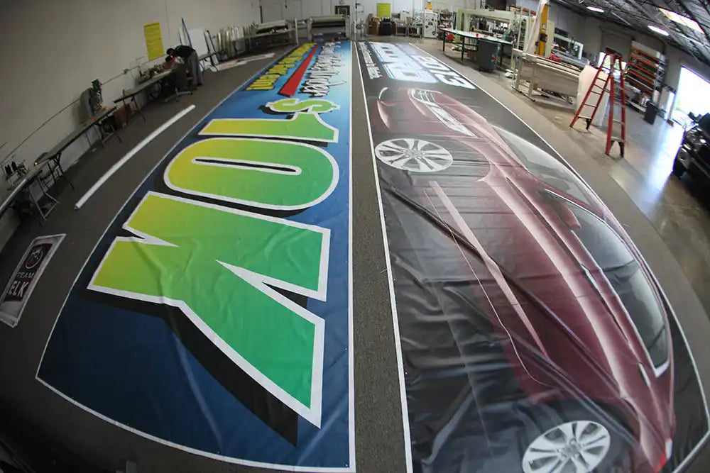 Two vehicle wraps laid out flat on a floor showing colorful graphics and designs.